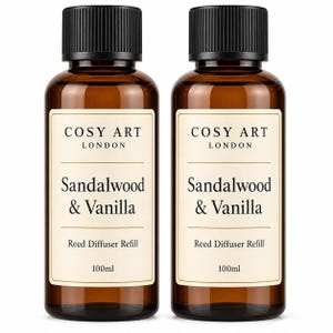 Könnte beinhalten: Zwei bernsteinfarbene Glasflaschen mit schwarzen Schraubverschlüssen, die jeweils 100ml Duftöl-Nachfüllung für Diffusoren enthalten. Die weißen Etiketten tragen den Text COSY ART LONDON, Sandalwood & Vanilla und Reed Diffuser Refill in Serifenschrift.