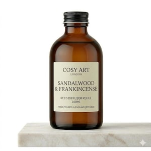 Może przedstawiać: Brązowa szklana butelka z czarną zakrętką zawierająca 100ml wkładu do dyfuzora zapachowego. Etykieta zawiera czarny napis COSY ART LONDON, SANDALWOOD & FRANKINCENSE, REED DIFFUSER REFILL, 100ml, HAND-POURED IN ENGLAND | EST. 2018.