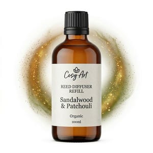Può includere: Un flacone in vetro ambrato da 100ml con tappo a vite nero contenente olio di ricarica per diffusore a bastoncini. L'etichetta riporta il testo Cosy Art, Reed Diffuser Refill, Sandalwood & Patchouli e Organic. Un'aura dorata circonda il flacone.