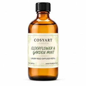 Könnte beinhalten: Eine braune Glasflasche mit schwarzem Verschluss, die Nachfüllflüssigkeit für einen Raumduft enthält. Das Etikett trägt die Aufschrift COSYART LONDON ELDERFLOWER & GARDEN MINT LUXURY REED DIFFUSER REFILL 100ml 3.38 fl oz HAND-POURED IN THE UK mit grünen Pflanzenmotiven.