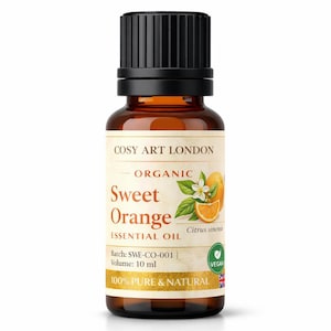 Peut inclure: Un flacon en verre ambré de 10 ml d'huile essentielle d'orange douce bio Cosy Art London. L'étiquette présente du texte, une illustration d'orange avec des feuilles et une fleur, un symbole vegan et le texte 100% pure & natural avec un petit drapeau britannique.