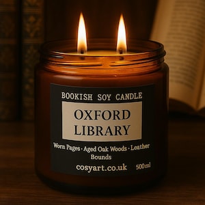 May include: A lit soy candle in a brown glass jar. The label reads "OXFORD LIBRARY" with the scent notes "Worn Pages, Aged Oak Woods, Leather Bounds." The candle has two wicks and is 500ml.