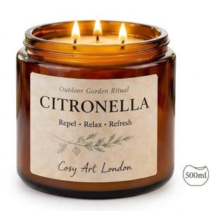 Puede incluir: Una vela de citronela encendida en un tarro de cristal marrón. La etiqueta dice "Outdoor Garden Ritual CITRONELLA" con las palabras "Repel • Relax • Refresh" y "Cosy Art London". El tarro tiene unos 10 cm de diámetro y contiene 500 ml.