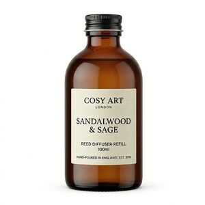 May include: A 100ml amber glass bottle with a black screw cap containing reed diffuser refill. The off-white label reads COSY ART LONDON, SANDALWOOD & SAGE, REED DIFFUSER REFILL, 100ml, and HAND-POURED IN ENGLAND | EST. 2018 in black text.