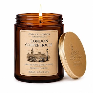 May include: A lit scented candle in a brown glass jar with a tan label reading COSY ART LONDON HOME FRAGRANCE LONDON COFFEE HOUSE LIBRARY BOOK & DARK COFFEE 200ml | 6.76 fl oz e. A gold metal lid with a London skyline logo sits beside the jar.