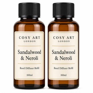 May include: Two amber glass bottles with black screw-top caps, each containing 100ml of reed diffuser refill. The white labels feature the text COSY ART LONDON, Sandalwood & Neroli, Reed Diffuser Refill, and 100ml in black and gold lettering.