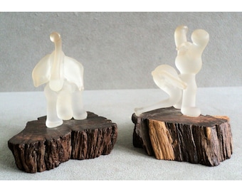 Può includere: Due figurine di elefanti in vetro trasparente su basi di legno. Gli elefanti sono in pose diverse, uno in piedi e l'altro in ginocchio. Le basi sono in legno scuro con una finitura naturale.