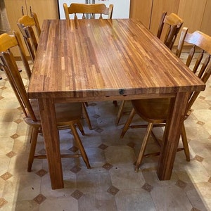 May include: A wooden dining table with a butcher block top and six chairs. The table is made of light brown wood and has a natural finish. The chairs are also made of wood and have a light brown finish.