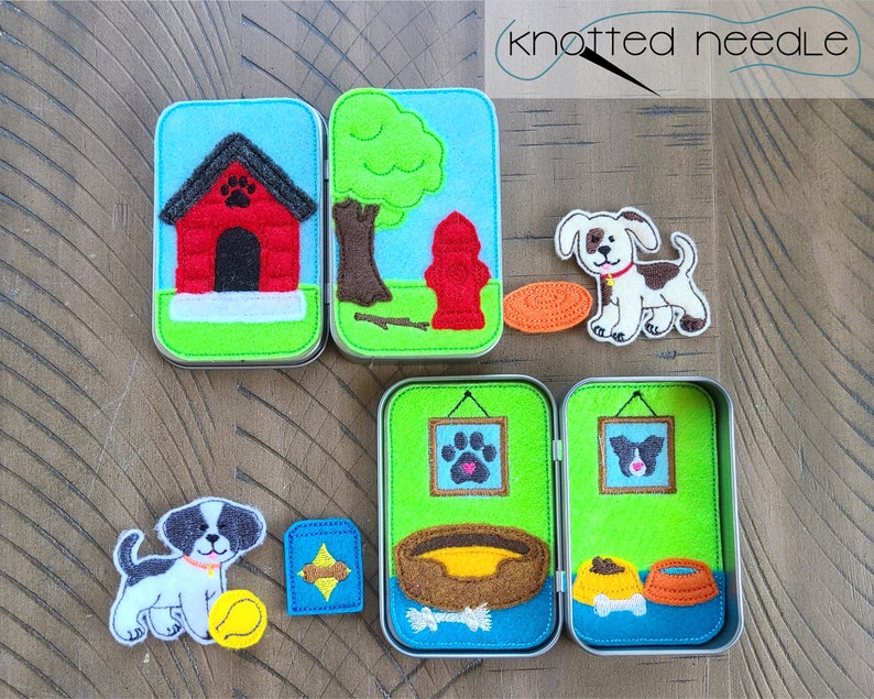 May include: A set of felt play scenes in a tin box, featuring a dog, a doghouse, a fire hydrant, a tree, a bowl of food, a bone, a dog bed, and a picture frame with a paw print. The set is perfect for imaginative play and storytelling.