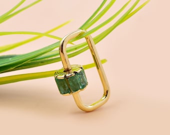 Könnte beinhalten: Goldfarbener Ring mit einem grünen Edelstein, der in einer quadratischen Form gefasst ist. Der Ring ist rechteckig mit abgerundeten Kanten.
