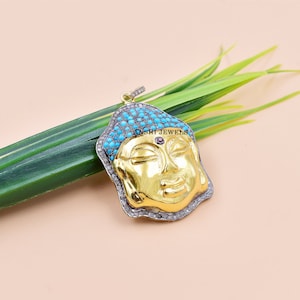 May include: Gold-toned Buddha pendant with turquoise and diamond accents. The pendant features a detailed face with closed eyes and a serene expression. The pendant is set in sterling silver and has a bail for attaching to a chain.