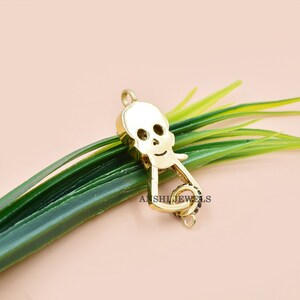 Puede incluir: Encanto de calavera de tono dorado con acentos de circonita c&uacute;bica negra. El encanto tiene un bucle en la parte superior para sujetarlo a un collar o pulsera.