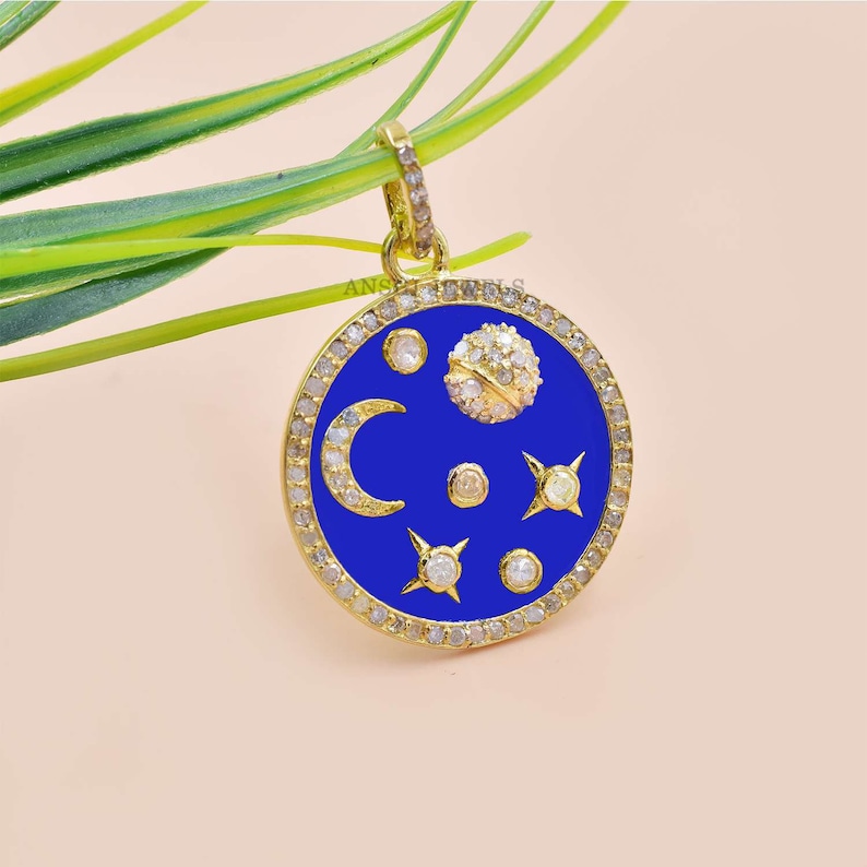 May include: Gold pendant necklace with a blue enamel circle featuring a crescent moon, stars, and a small round stone set with diamonds. The circle is surrounded by a row of diamonds.