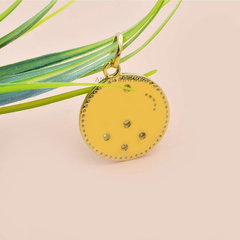 May include: A gold pendant with a circular design featuring a small cluster of clear gemstones. The pendant has a textured border and a loop at the top for attaching a chain.