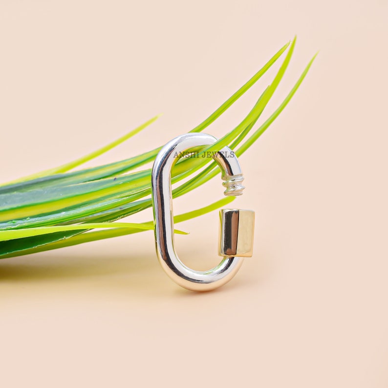 May include: A silver and gold oval-shaped clasp with a spring-loaded gate. The clasp is made of metal and has a polished finish. The clasp is a popular accessory for jewellery making and can be used to connect chains, bracelets, and other jewellery pieces.