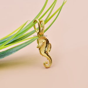 May include: A gold-colored seahorse pendant charm. The pendant is detailed with a textured surface and a loop for attaching to a chain.