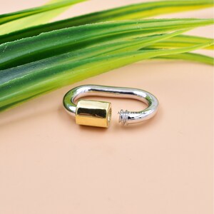 May include: A silver and gold oval-shaped ring with a textured design. The ring is made of two different metals, with a gold band on one side and a silver band on the other.