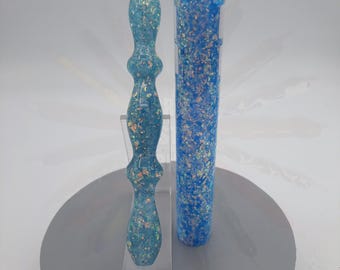 May include: Two blue and iridescent glitter resin pens, one with a rounded tip and the other with a straight tip. The pens are on a gray surface.