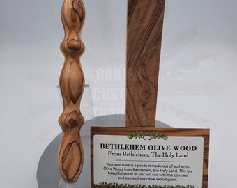 May include: A wooden pen made from olive wood from Bethlehem, The Holy Land. The pen is brown with a natural wood grain. The text on the card reads "BETHLEHEM OLIVE WOOD From Bethlehem, The Holy Land Your purchase is a product made out of authentic Olive Wood from Bethlehem, the Holy Land. This is a beautiful wood as you will see with the contrast and swirls of the Olive Wood grain."