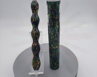 May include: Two black and green pen blanks with iridescent glitter. One pen blank is a straight cylinder and the other is a wavy cylinder.