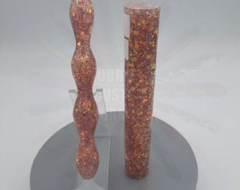 May include: A copper-colored, glitter-filled diamond painting pen with a clear tip and a matching tube of glitter. The pen has a curvy, ergonomic design. The tube is cylindrical and filled with the same glitter.