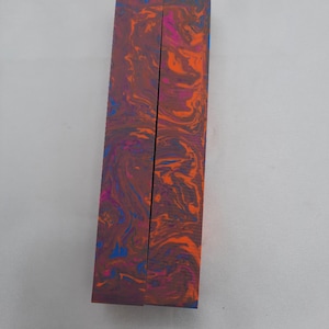 May include: Two wooden pen blanks with a marbled pattern in shades of orange, pink, and blue.