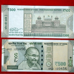 Puede incluir: Dos billetes indios de 500 rupias. El billete superior presenta una ilustración de un edificio y el texto "RESERVE BANK OF INDIA FIVE HUNDRED RUPEES". El billete inferior presenta el retrato de Mahatma Gandhi.