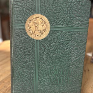 May include: Green hardcover book with a gold emblem of a knight on horseback. The book has a textured cover with a cross design and the words "Brier Patch 1930" embossed on the front.