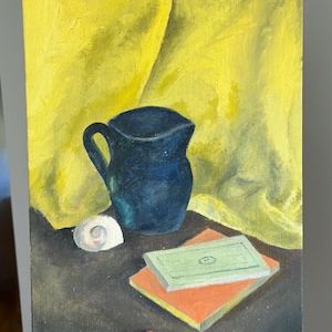 May include: An oil painting on canvas depicting a dark blue ceramic pitcher, a small white seashell, and two stacked rectangular books with orange and light green covers, all set against a bright yellow draped fabric background.