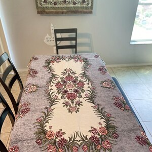 Pode incluir: Um corredor de mesa floral cinza e branco com um centro creme. O corredor apresenta um padrão repetitivo de flores rosa e verdes.