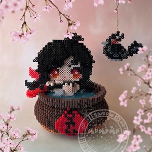 May include: A beaded figure of a girl with black hair and red eyes, sitting in a brown pot with red and white accents. The figure is surrounded by pink cherry blossoms.