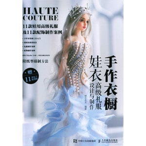 Op de afbeelding: Een boekomslag met een pop die een blauwe en witte jurk draagt met parelversiering. De titel van het boek is "Haute Couture" en de ondertitel is "11款娃用高级礼服及11款配饰制作案例".