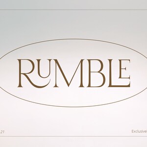 May include: A brown oval with the word "RUMBLE" in a serif font. The text is in a light brown color and is centered in the oval. The background is a light gray color. The text "Date 17 March 21" is at the bottom left of the image and the text "Exclusively on this platform" is at the bottom right of the image.