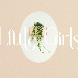 May include: A white oval with the text "Little Girls" in a decorative font. A small wooden crate with a green plant growing out of it is inside the oval.