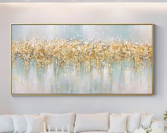 Op de afbeelding: Een groot rechthoekig horizontaal wandkunstwerk met een abstract ontwerp met gestructureerde bladgoudaccenten, witte accenten en zacht blauwgrijze verticale verfdruppels, alles ingesloten in een dunne, goudkleurige metalen lijst.