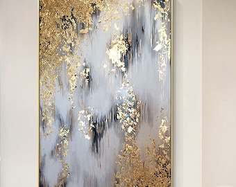 May include: A rectangular wall painting featuring an abstract composition of white, gray, and black vertical brushstrokes accented with textured gold leaf flakes. The artwork is enclosed in a thin gold frame and mounted on a plain white wall.