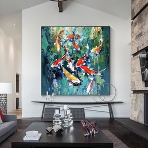 May include: Large abstract painting of koi fish in a pond. The artwork features vibrant orange, red, white, and yellow fish against a backdrop of green and blue brushstrokes. The painting is displayed in a modern living room.