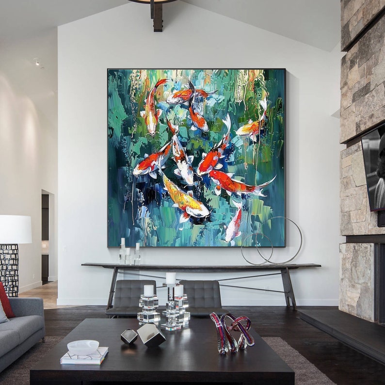 May include: Large abstract painting of koi fish in a pond. The artwork features vibrant orange, red, white, and yellow fish against a backdrop of green and blue brushstrokes. The painting is displayed in a modern living room.
