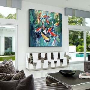 May include: Large square oil painting featuring koi fish in a pond. The fish are orange, white, and yellow, set against a green and blue background. The artwork hangs above a white and silver cabinet in a modern living room.
