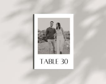 May include: Monochrome table number card featuring a photograph of a couple walking. The card displays "TABLE 30" in a serif font. The image has a shadow overlay.