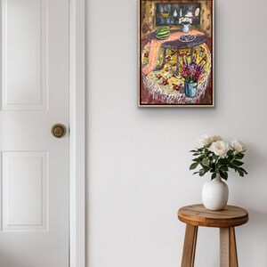 May include: An oil painting depicts a round table with a yellow floral tablecloth, a watermelon, and a vase of flowers. A small wooden stool holds a white vase with white roses. A white door is on the left.