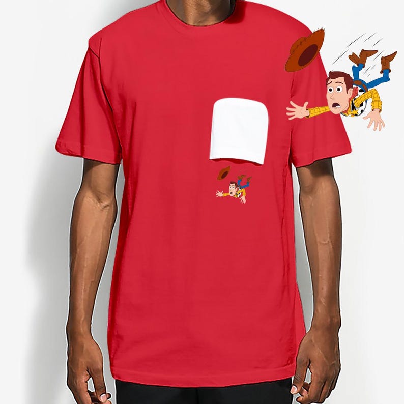 May include: A red t-shirt featuring a white pocket design and a cartoon illustration of Woody from Toy Story. The graphic shows Woody falling, with his hat and boots in the air. The shirt is short-sleeved.