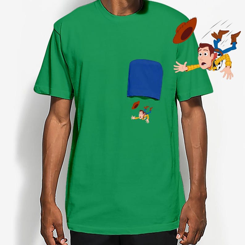 May include: Green t-shirt featuring a blue pocket design with a cartoon illustration of a character falling out of the pocket. The character is wearing a cowboy hat, a yellow shirt, and blue jeans.