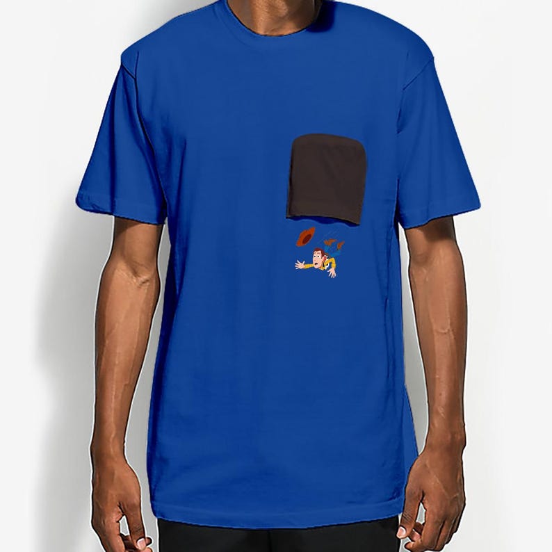 May include: Royal blue t-shirt with a black pocket and a cartoon graphic of a character with a cowboy hat and a red object. The graphic is located below the pocket.