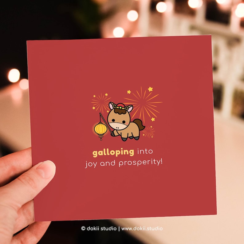 May include: A red card featuring a cartoon horse holding a lantern, with fireworks and stars. The text reads "galloping into joy and prosperity!" The card is held by a hand.