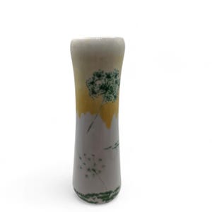 May include: A ceramic vase with a white, yellow, and gray color scheme. The vase features green dandelion designs. The vase has a cylindrical shape and is suitable for displaying flowers or as a decorative item.