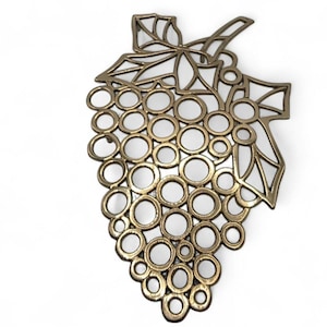 May include: A gold-colored metal grape cluster-shaped decorative item. The design features a series of connected circles to represent the grapes, with leaves at the top. The item is likely a wall hanging or decorative piece.