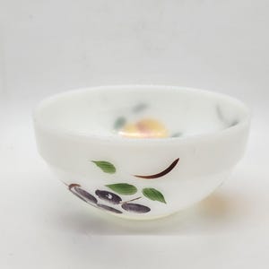 May include: A white milk glass bowl with a hand-painted design of fruit and leaves. The bowl has a slightly scalloped rim and is in good condition.