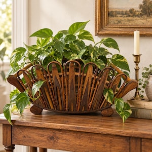 May include: A semi-circular brown bamboo basket with a scalloped edge design, featuring vertical slats and a woven base. The basket is filled with a lush green pothos plant with variegated leaves, creating a dense foliage display.