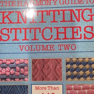 May include: A book cover titled "The Harmony Guide to Knitting Stitches, Volume Two." The cover is light blue with red text. Several knitting stitch examples are displayed in small squares, showcasing various textures and patterns.